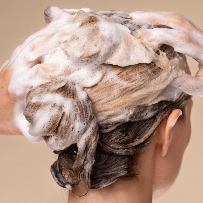 Person with soapy hair on a beige background