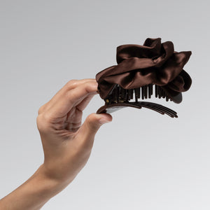 Hand holding a Satin Rosette Medium Flat Cloud Clip in Chocolate against a neutral background