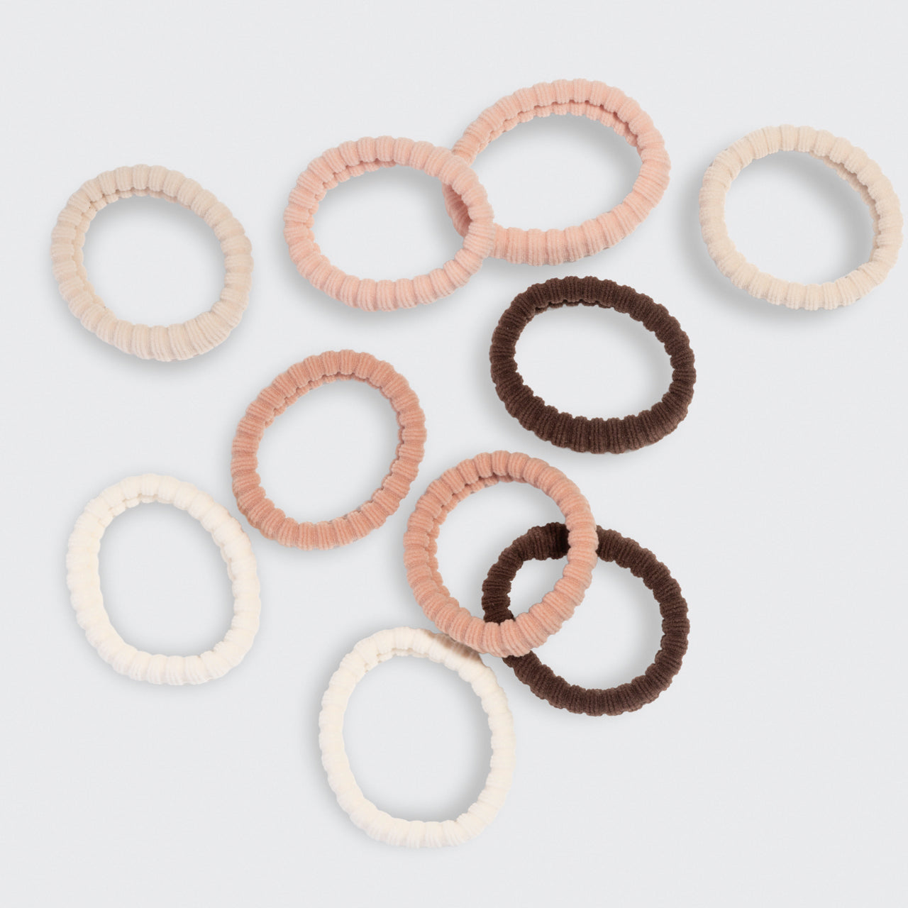 Set of cream, beige, blush, and brown hair ties on a light gray background