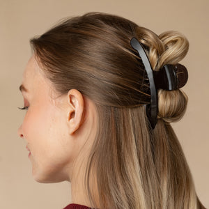 Model wearing Kitsch Translucent Black Arched Claw Clip - Large securing blonde hair in a half-up twist