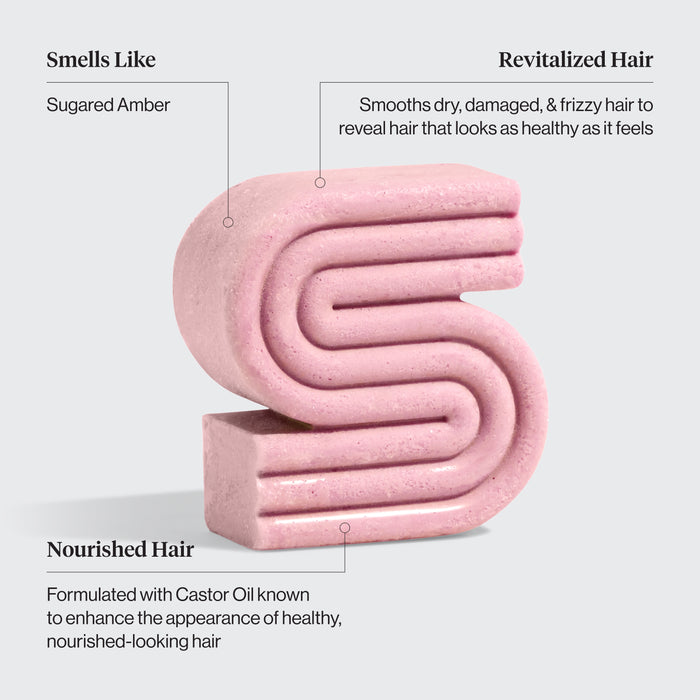 Pink Kitsch castor oil solid shampoo bar with text describing its benefits on a light gray background. Benefits are: Smells like sugared amber, revitalized hair smooths dry, damaged, and frizzy hair to reveal hair that looks as healthy as it feels, and Nourished hair formulated with castor oil known to enhance the appearance of healthy, nourished-looking hair