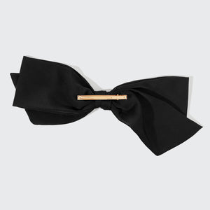 Black bow tie with a gold clasp on a light gray background
