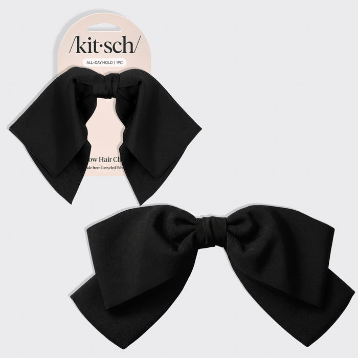 A black bow hair clip shown both on its retail backing card and as a loose product shot, on a light gray background. The brand name 'kitsch' is visible on the card.