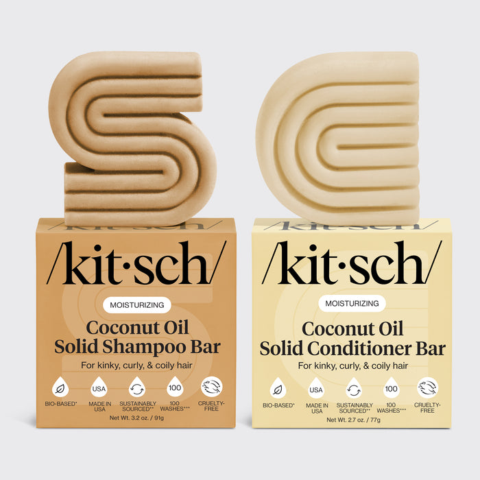 Kitsch coconut oil solid shampoo and conditioner bars on top of their packaging side by side on a light gray background.
