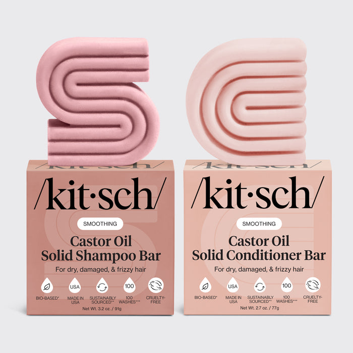 Two pink kitsch castor oil shampoo and conditioner bars with their respective boxes on a light gray background