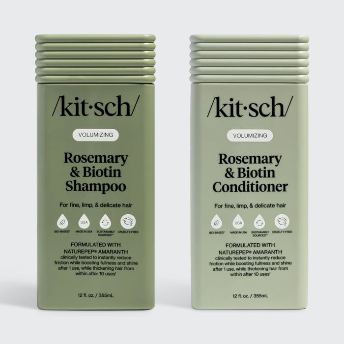 Two sage-green rectangular bottles of Kitsch Volumizing Rosemary & Biotin Shampoo and Conditioner for fine, limp, and delicate hair. The labels highlight the use of NaturePep Amaranth, noting it is clinically tested to reduce friction and boost fullness. The bottles feature icons for bio-based, made in USA, sustainably sourced, and cruelty-free.