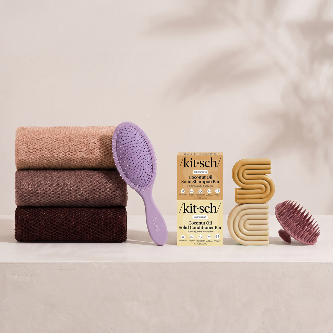 Kitsch Spring Welcome Kit Coconut Oil shown as a full bundle with the Moisturizing Coconut Oil Shampoo and Conditioner Bars, Soft Violet Wet/Dry Brush, Terracotta Scalp Exfoliator and Rosewood African Net Sponge on a soft neutral background